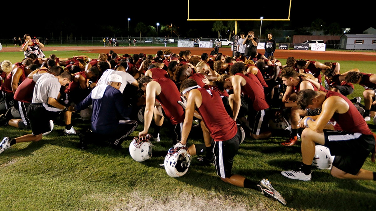 Members of the Marjory Stoneman Douglas High School football team pray together as they began practice for a new season
