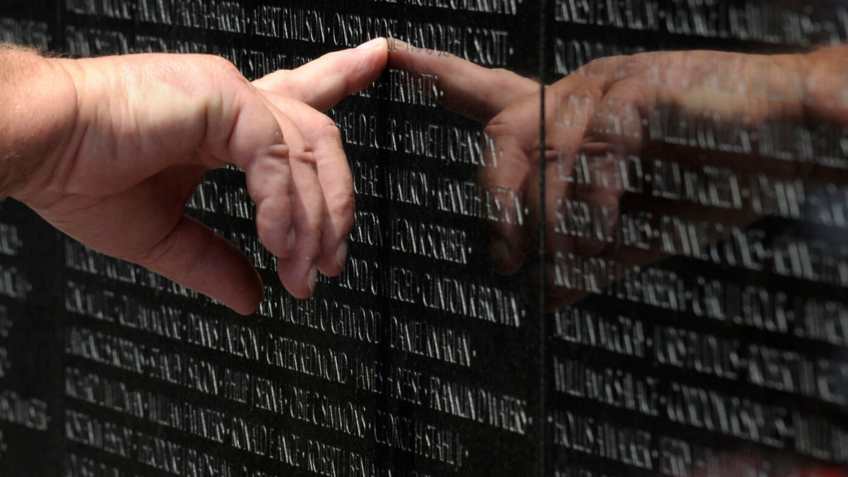 A visitor to the Vietnam Veteran's Memorial touches the name of a fallen soldier etched on the wall of the memorial in Washington, Friday, May 25, 2012. On Monday, the Vietnam Veterans Memorial Wall will begin the national commemoration of the Vietnam Warâs 50th anniversary. (AP Photo/Susan Walsh)