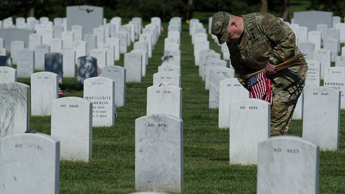 Army Chief of Staff Gen. Mark Alexander Milley places flags at gravesite as the Army 3d U.S. Infantry Regiment, The Old Guard, honor the nation's fallen military heroes during its annual Flags In ceremony at Arlington National Cemetery, May 24, 2018. (AP Photo/Cliff Owen)