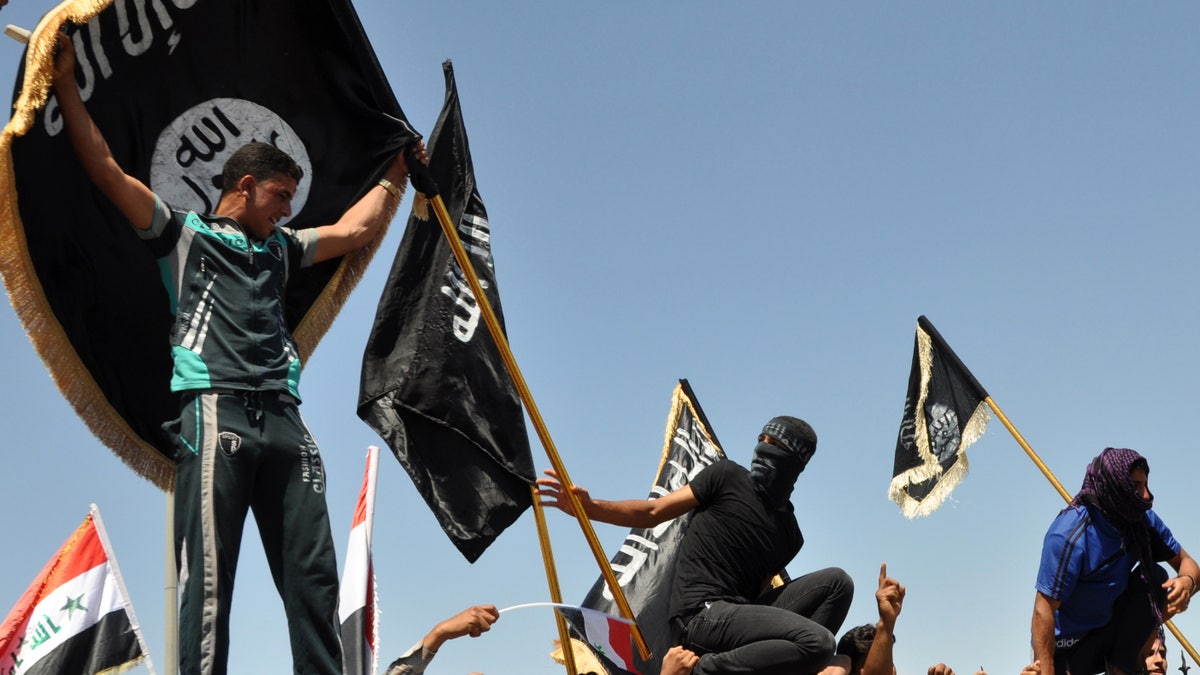 Masked Sunni protesters wave Islamist flags while others chant slogans at an anti-government rally in Fallujah, Iraq, Friday, April 26, 2013. The leader of Al Qaeda's Iraq arm, Abu Bakr al-Baghdadi, defiantly rejected an order from the terror network's global command to scrap a merger with the organization's Syria affiliate, according to a message purporting to be from Al-Baghdadi that was posted online Saturday, June 15, 2013. 