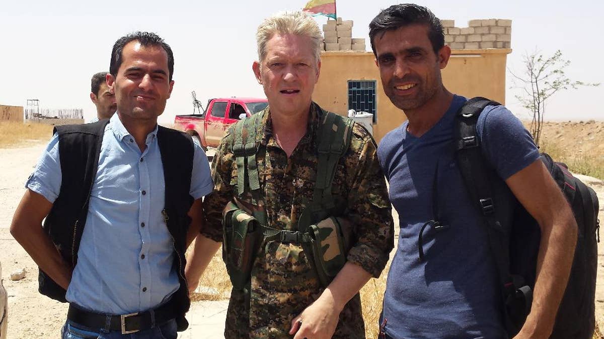 In this handout photo provided by Kurdish journalist Mohammed Hassan, taken on May 19, 2015, Michael Enright, center, a British actor who has had minor roles in Hollywood films, wears the Kurdish fighters military uniform after he joined them battling against the Islamic State group, near Tel Tamr town, northeast Syria. Enright, who played a deckhand in “Pirates of the Caribbean: Dead Man’s Chest,” appears in a video released by the Kurdish People’s Protection Units, known as the YPG. The video shows him in a trench with other fighters firing an assault rifle. (Mohammed Hassan via AP )