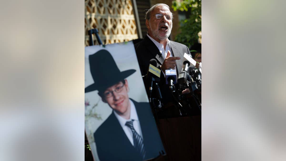 New York assemblyman Dov Hikind addresses a gathering as he stands near a photograph of Aaron Sofer, 23, Tuesday, Aug. 26, 2014, in Lakewood, N.J. Israeli police said Tuesday they are searching for the young New Jersey religious student who went missing in Israel during a hike in a forest outside Jerusalem last week. Sofer of Lakewood, New Jersey, has been missing since Friday when he went on a hike with a friend in the Jerusalem Forest, said police spokesman Micky Rosenfeld. (AP Photo/Mel Evans)