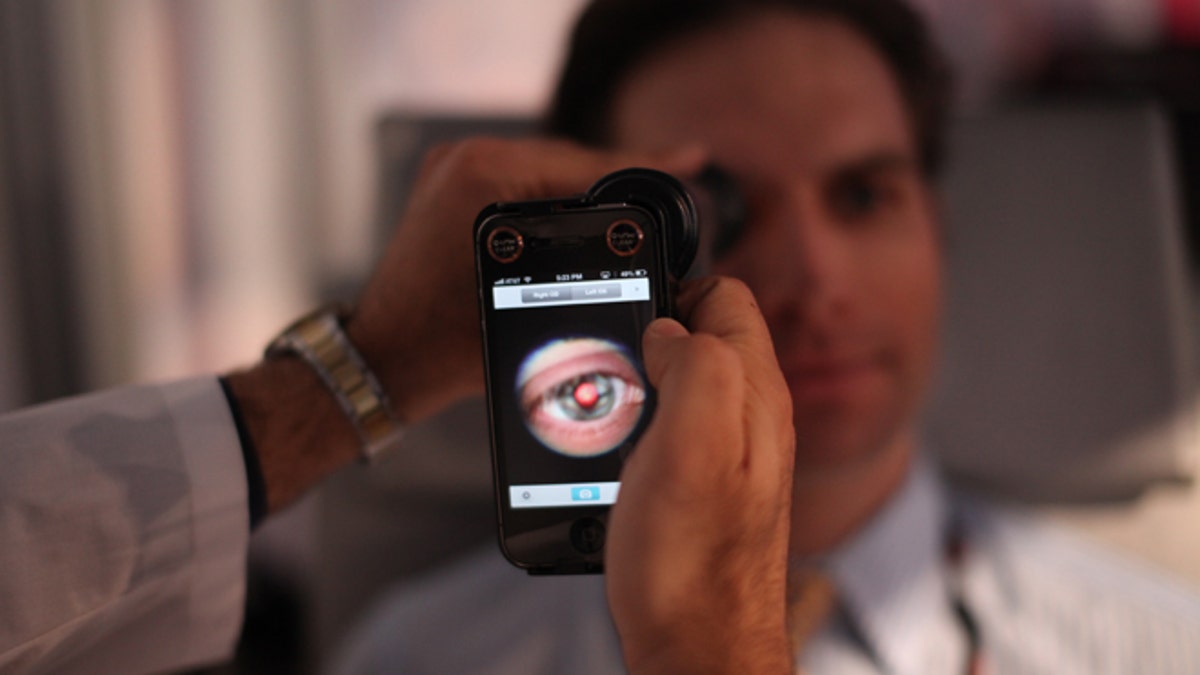 This image provided by TEDMED, shows a medical student preparing to photograph the inside of someone's eye using a special tool that taps a smartphoneâs camera during a recent TEDMED conference in Washington. Companies are developing a variety of miniature medical tools that hook onto smartphones to provide almost a complete physical. The hope is that this mobile medicine will help doctors care for patients in new ways, and also help people better monitor their own health. (AP Photo/TEDMED)
