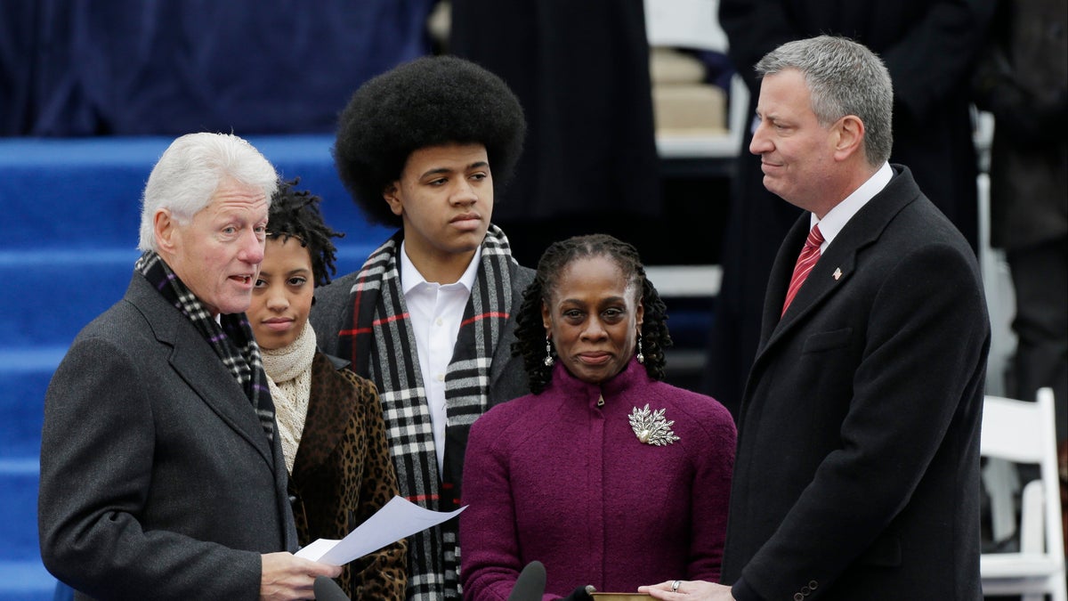 Former President Bill Clinton, left, speaks before he administers the oath of office to Mayor-elect Bill de Blasio, right, as Chiara de Blasio, second from left, Dante de Blasio, center, and wife Chirlane McCray, second from right, watch on the steps of City Hall Wednesday, Jan. 1, 2014, in New York.  (AP Photo/Frank Franklin II)