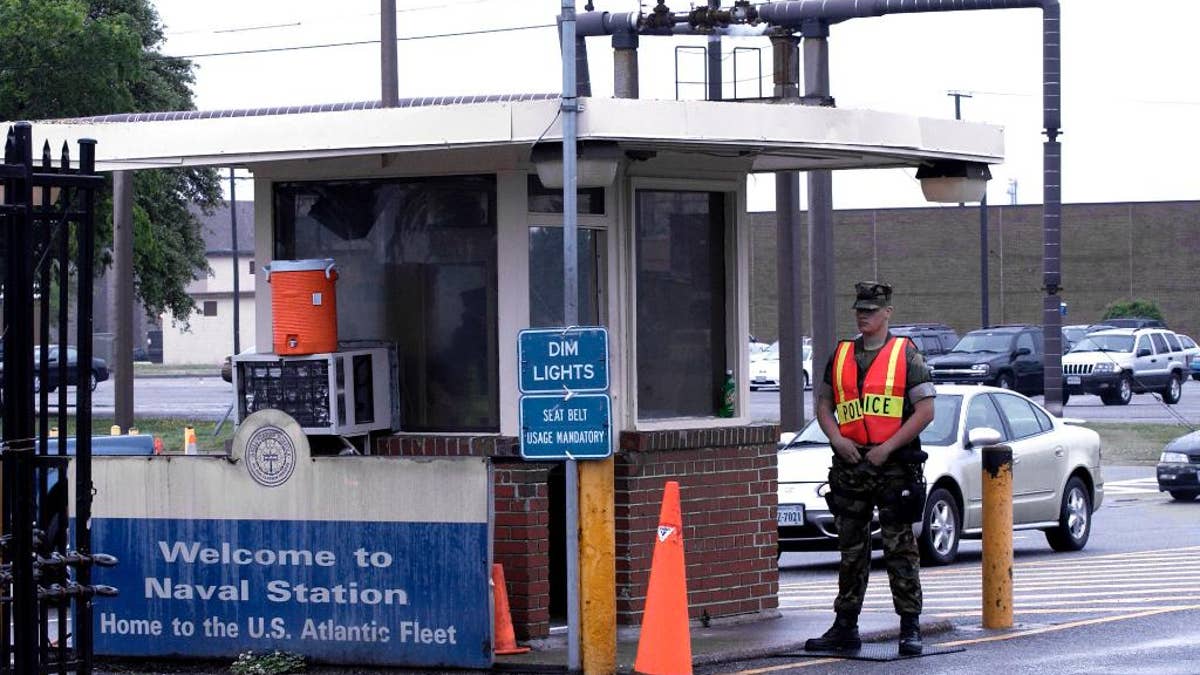 In this May 3, 2004 file photo, security personnel wait to inspect vehicles entering Norfolk Naval Station in Norfolk, Va. A sailor was fatally shot at the world's largest naval base late Monday, March 24, 2014, and security forces killed a male civilian suspect, base spokeswoman Terri Davis said. 