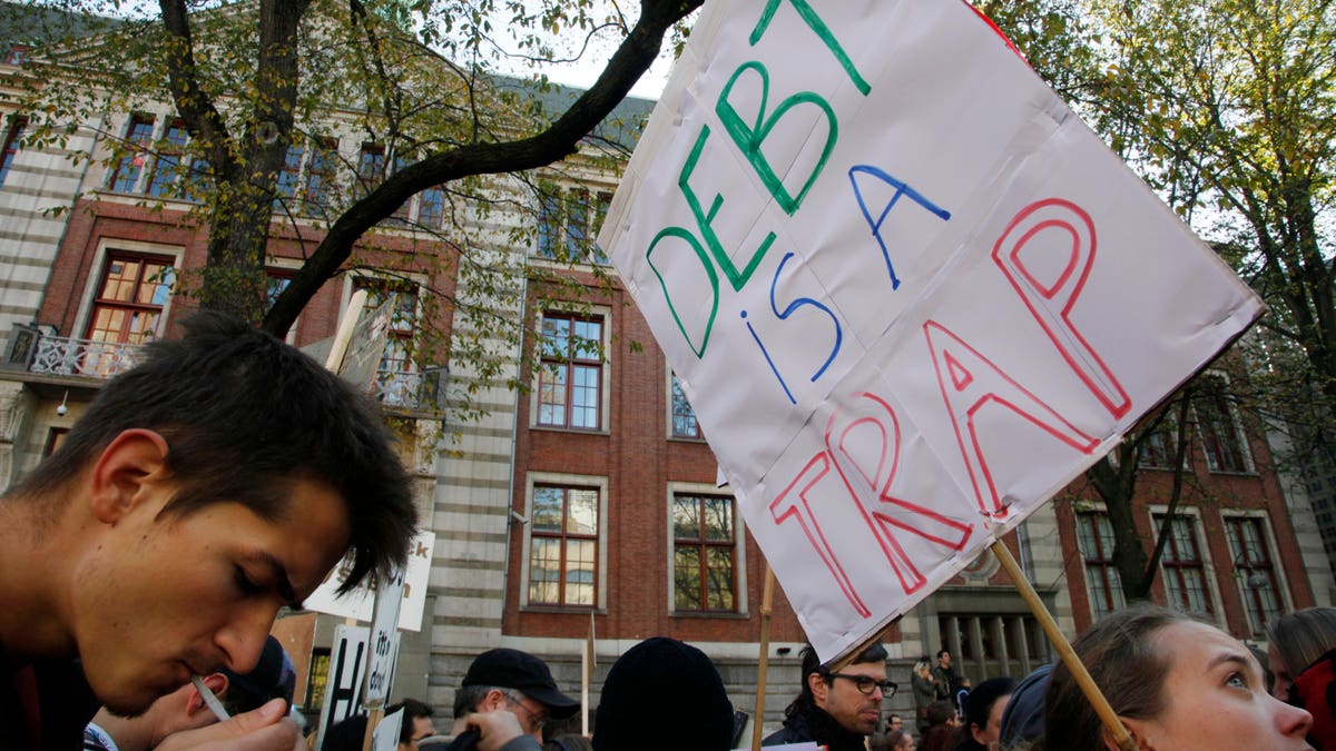 Demonstrators hold placards outside the NYSE Euronext stock exchange, rear, in Amsterdam, Netherlands, Saturday Oct. 15, 2011, during a demonstration in support of the Occupy Wall Street movement.
