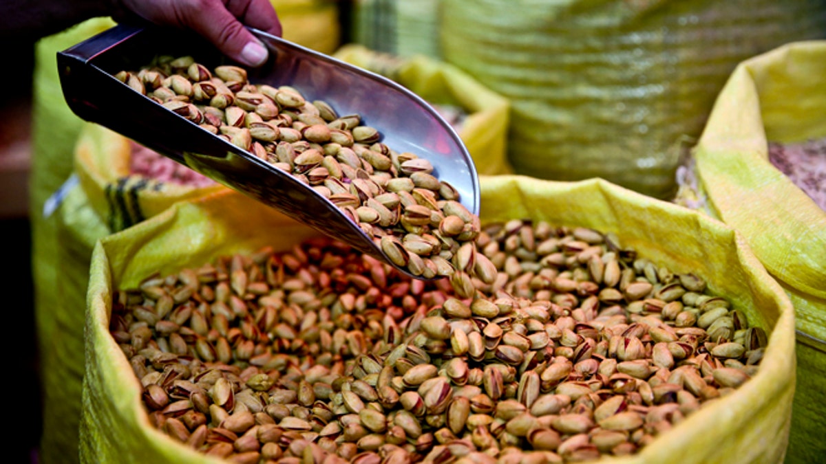 FILE - In this March 31, 2013 file photo, a shopkeeper sells pistachios at his shop in western Tehran, Iran. Help yourself to some nuts this holiday season: Regular nut eaters were less likely to die of cancer or heart disease, in fact, were less likely to die of any cause during a 30-year Harvard study. (AP Photo/Ebrahim Noroozi, File)