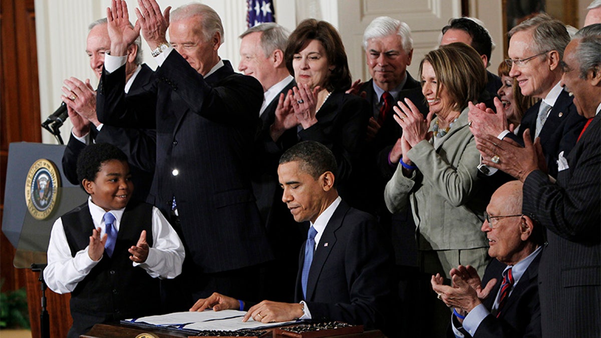 In this March 23, 2010, file photo President Obama is applauded after signing the Affordable Care Act into law in the East Room of the White House in Washington.