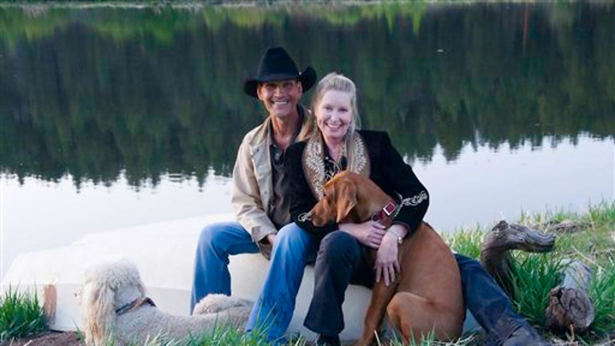 FILE - In this May 13, 2009 file photo originally released by WKT Public Relations, Patrick Swayze, left, and his wife Lisa Niemi pose with their dogs, poodle Lucas, left, and Rhodesian Ridgeback puppy Kumasai at their ranch in New Mexico. Swayze's publicist Annett Wolf says the 57-year-old 