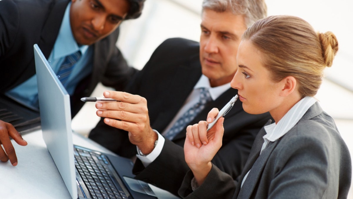 Successful group of business colleagues working on a laptop