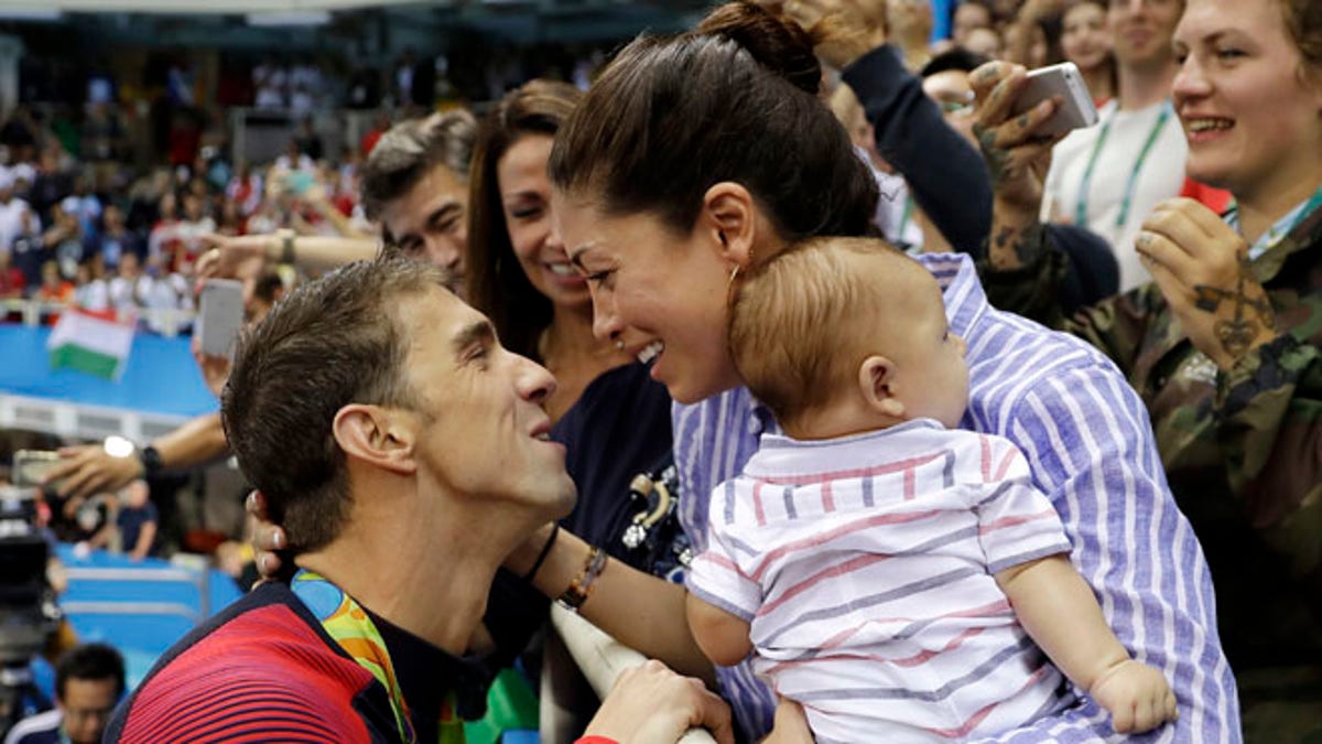FILE - In this Aug. 9, 2016, file photo, United States' swimmer Michael Phelps celebrates winning his gold medal in the men's 200-meter butterfly with his fiance Nicole Johnson and baby Boomer during the swimming competitions at the 2016 Summer Olympics, in Rio de Janeiro, Brazil. Phelps shared an Instagram picture on Oct. 30, 2016, of his beach wedding to Johnson that took place months after the couple got legally married in Arizona. (AP Photo/Matt Slocum, File)