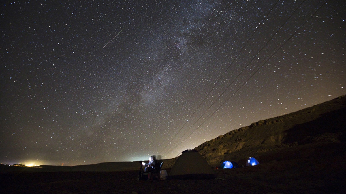 File photo - a meteor streaks across the sky in the early morning as people watching during the Perseid meteor shower in Ramon Carter near the town of Mitzpe Ramon, southern Israel, Aug.13, 2015. 