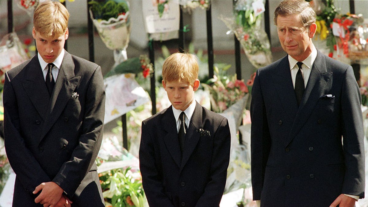 Prince Charles (R), Prince Harry (C) and Prince William look at the coffin of Diana, Princess of Wales, after it was placed into a hearse September 6. Hundreds of thousands of mourners lined the streets of Central London to watch the funeral procession. The Princess died last week in a car crash in Paris. - PBEAHUMOWCI