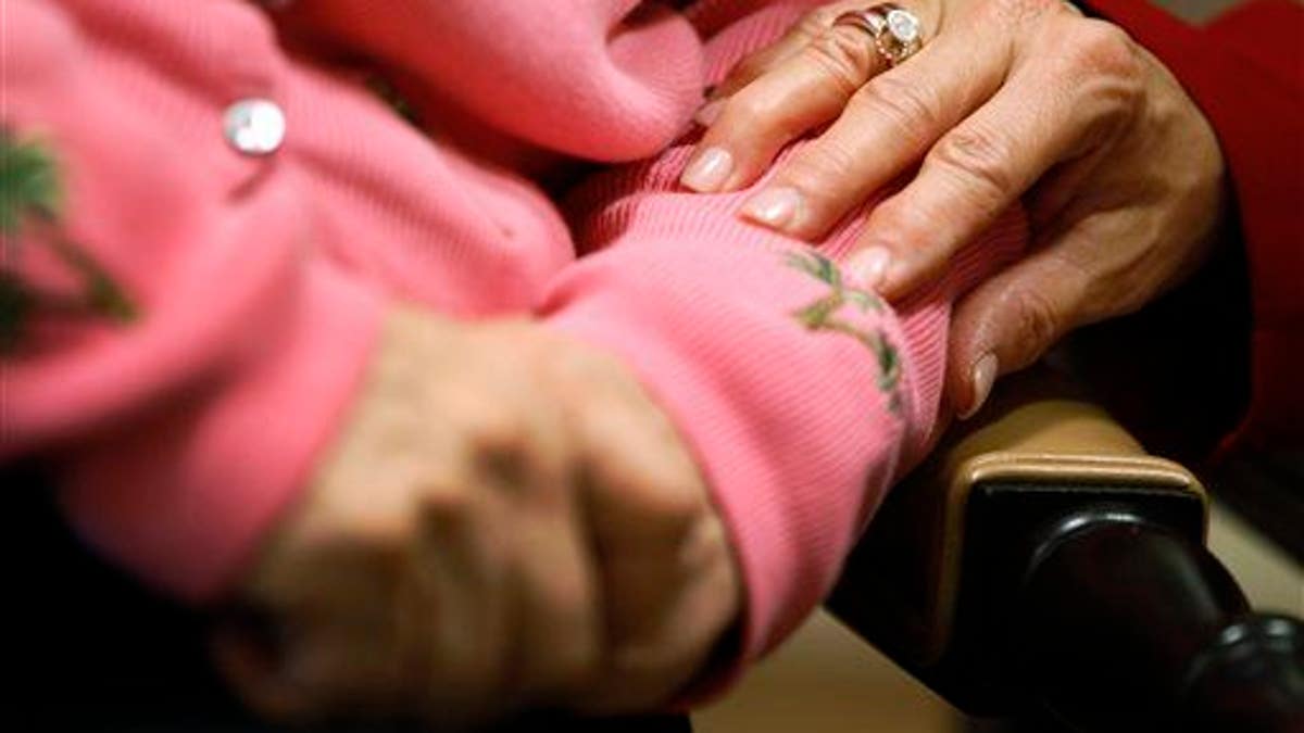 Uma funcionária de um centro de repouso para pacientes com Alzheimer coloca a mão no braço de um residente