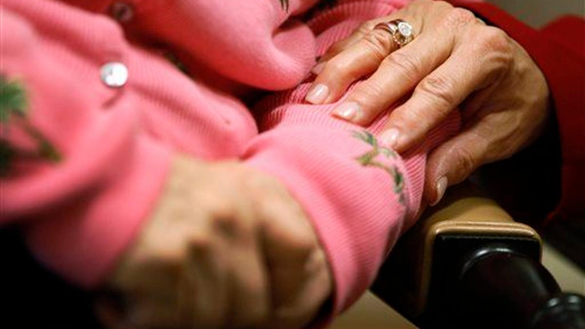 A worker at an Alzheimer's assisted-living site puts her hand on the arm of a resident