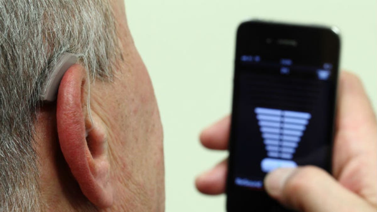 An employee of GN, the world's fourth largest maker of hearing aids, demonstrates the use of ReSound LiNX in Vienna November 22, 2013. (REUTERS/Heinz-Peter Bade)