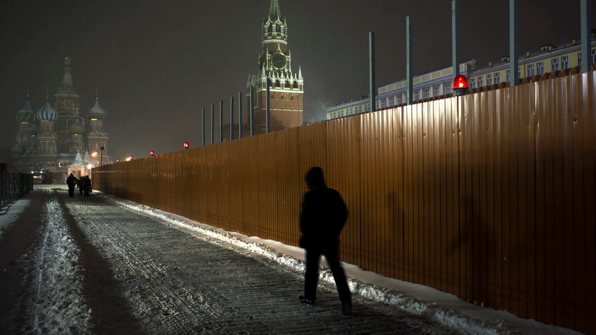 People walk past a fence around the Lenin Mausoleum in Red Square, with St. Basil Cathedral partially seen at left, in Moscow, Russia, early Thursday, Nov. 29, 2012. A snowfall hit Moscow on Wednesday with temperatures falling to about 0 Centigrade (32 degrees Fahrenheit). (AP Photo/Alexander Zemlianichenko)