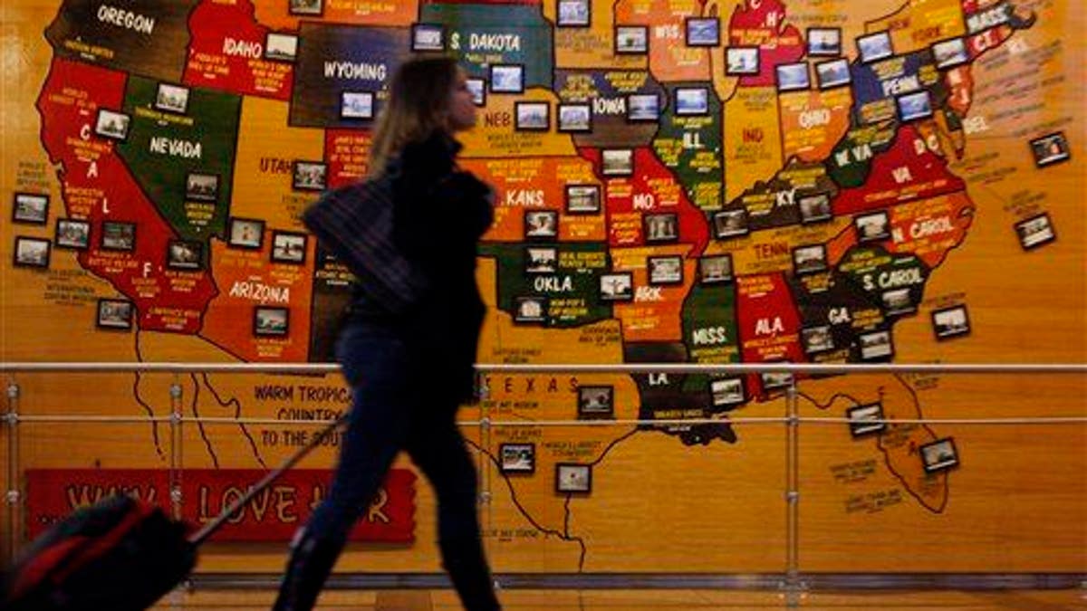A passenger rolls past a map of the United States of America on the way to the security lines at Denver International Airport.