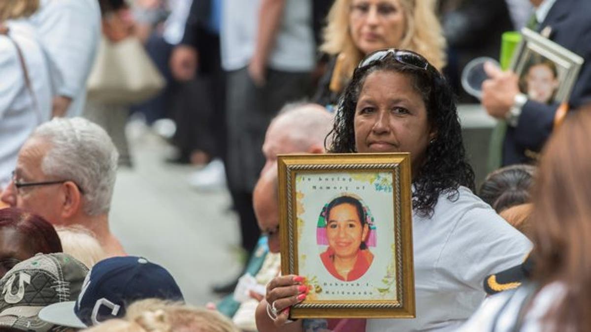 FILE- In this Sept. 11, 2015 file photo, a woman holds up a photograph during the ceremony commemorating the Sept. 11, 2001 terrorist attacks at the World Trade Center site in New York. Victims' relatives and dignitaries will once again convene Sunday, Sept. 11, 2016, on the memorial plaza at the World Trade Center for one of the constants in how America remembers 9/11 after 15 years, the anniversary ceremony itself. (AP Photo/Bryan R. Smith, File)