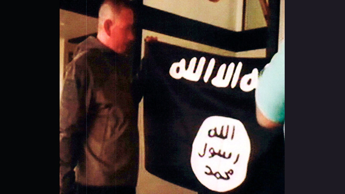 Army Sgt. 1st Class Ikaika Kang holds an Islamic State group flag after allegedly pledging allegiance to the terror group at a house in Honolulu.