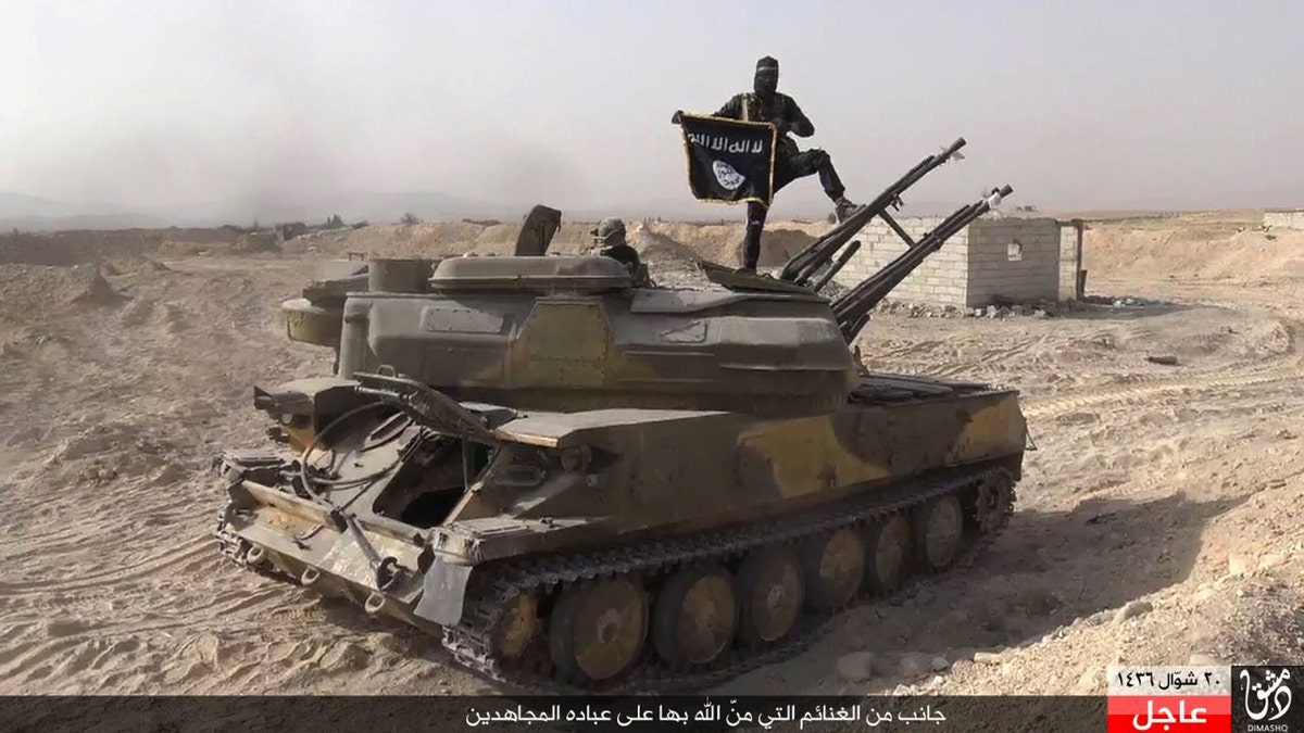 In this picture released on Aug. 5, 2015 by the Rased News Network, a Facebook page affiliated with ISIS, an ISIS militant stands on a tank captured from Syrian government forces, in the town of Qaryatain southwest of Palmyra, central Syria. 