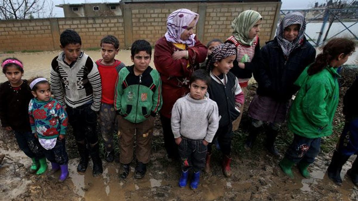 Syrian refugees pose for a photograph after their tents flooded from the rain, at a temporary refugee camp, in the eastern Lebanese town of Al-Faour near the border with Syria. 