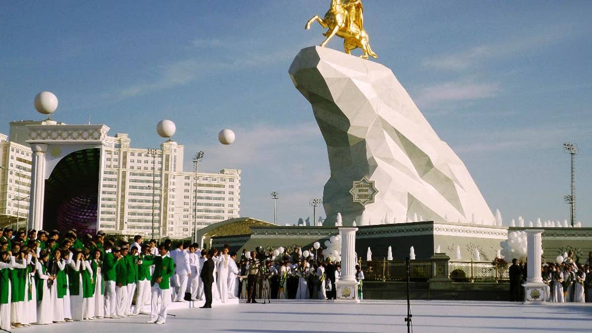 People gather for the monument unveiling ceremony in Ashgabat, Turkmenistan Monday, May 25, 2015. The isolated energy-rich Central Asian nation of Turkmenistan has unveiled a gold-leafed statue of the president in a gesture intended to burnish the leaders burgeoning cult of personality. The 21-meter monument presented to the public Monday consists of a statue of President Gurbanguly Berdymukhamedov atop a horse mounted on a towering pile of marble. (AP Photo/Alexander Vershinin)
