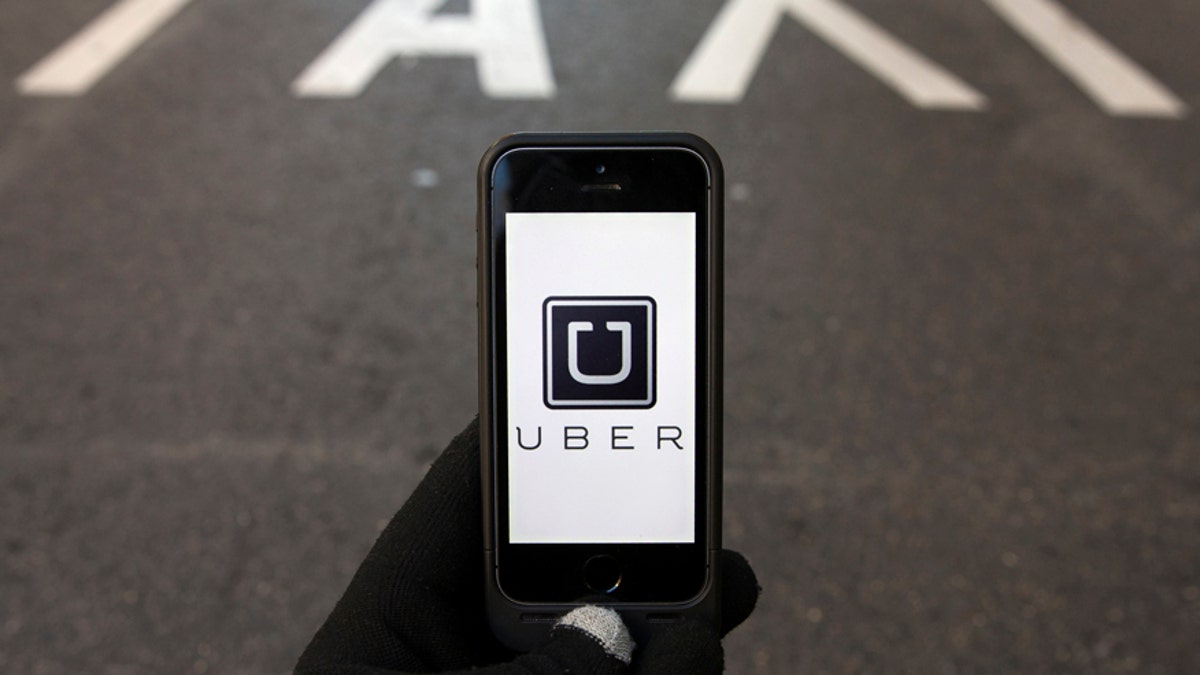File photo - The logo of car-sharing service app Uber on a smartphone over a reserved lane for taxis in a street is seen in this photo illustration taken in Madrid on Dec. 10, 2014. 