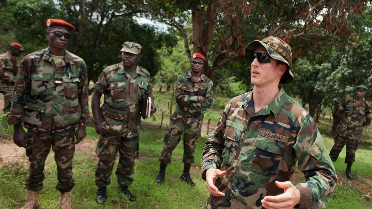 FILE - In this Sunday, April 29, 2012 file photo, U.S. Army special forces Captain Gregory, 29, from Texas, right, who would only give his first name in accordance with special forces security guidelines, speaks with troops from the Central African Republic and Uganda who are searching for Joseph Kony's Lord's Resistance Army (LRA), in Obo, Central African Republic. The Obama administration said Tuesday, Jan. 6, 2015 that it has taken into custody a man claiming to be Dominic Ongwen, a top member of Joseph Kony's Lord's Resistance Army who is wanted by the International Criminal Court, after the man surrendered to U.S. forces in the Central African Republic. (AP Photo/Ben Curtis, File)
