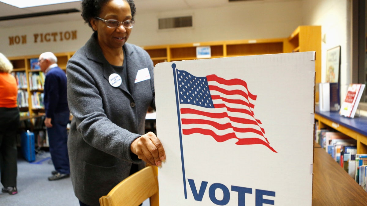 An election worker sets up a voting booth in the library of Spring Hill Elementary School, which is being used as a polling station in McLean, Virginia.