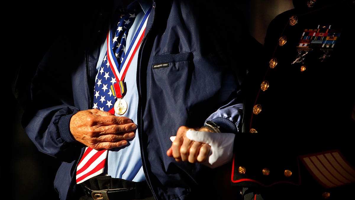 Marine Corps veteran Jim Brown, 83, (right) who served in Vietnam and Korea helps D-Day Veteran Howard Mills, 91, to the stage for special recognition during a Veteran's Day ceremony organized by Forever Young Senior Veteran Wish at Collierville Town Square in Collierville, Tenn. Sunday, Nov. 10, 2013. (AP Photo/The Commercial Appeal, Jim Weber)