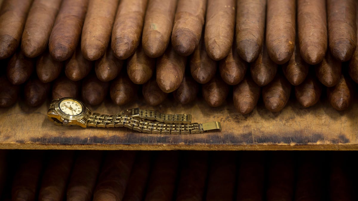 In this Feb. 26, 2015 photo, an employee's watch sits next to a stack of cigars at the Corona cigar factory in Havana, Cuba. Cuban cigar makers are licking their chops over new U.S. rules that let more Americans travel to the island and legally bring back as much as $100 worth in prized stogies for the first time in decades. (AP Photo/Ramon Espinosa)