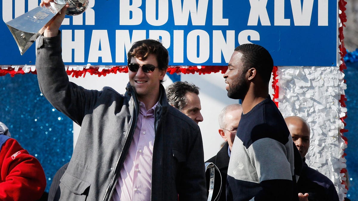 NEW YORK, NY - FEBRUARY 07: Quarterback Eli Manning #10 (L) of the New York Giants and Super Bowl XLVI MVP holds the Vince Lombardi Trophy as Justin Tuck #91 (R) of the New York Giants looks on during the Giants' Victory Parade on February 7, 2012 in New York City. The Giants defeated the New England Patriots 21-17 in Super Bowl XLVI. (Photo by Andrew Burton/Getty Images)