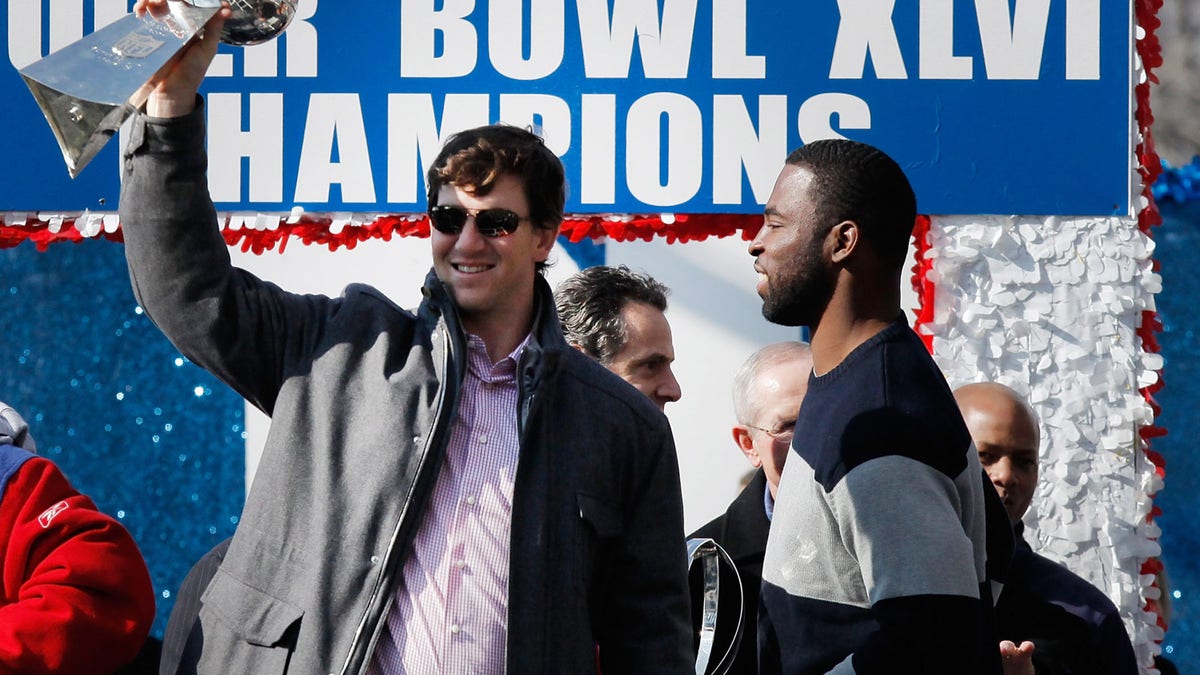 NEW YORK, NY - FEBRUARY 07: Quarterback Eli Manning #10 (L) of the New York Giants and Super Bowl XLVI MVP holds the Vince Lombardi Trophy as Justin Tuck #91 (R) of the New York Giants looks on during the Giants' Victory Parade on February 7, 2012 in New York City. The Giants defeated the New England Patriots 21-17 in Super Bowl XLVI. (Photo by Andrew Burton/Getty Images)