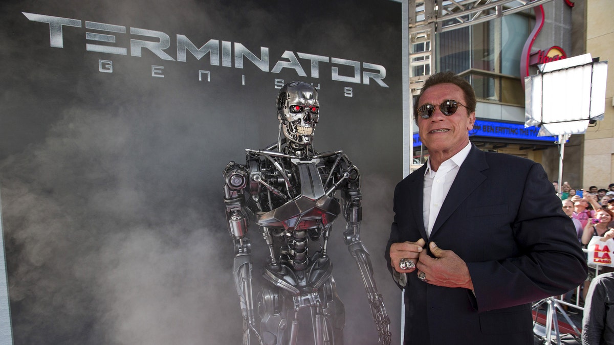 Cast member Arnold Schwarzenegger poses by a Terminator replica at the premiere of 