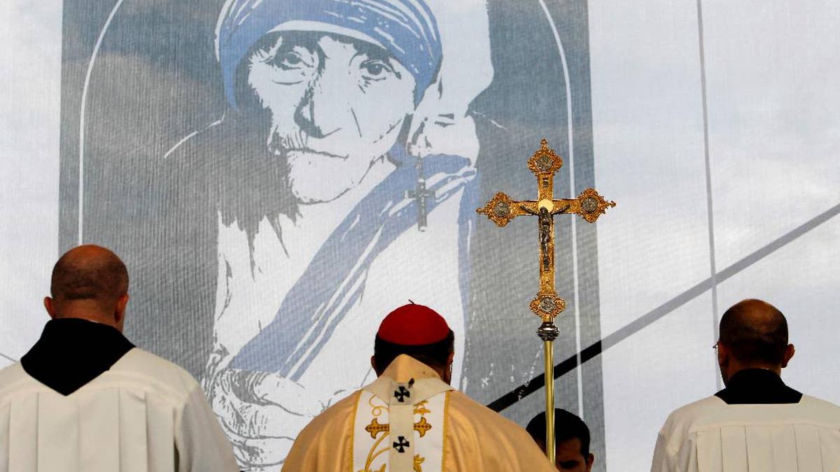 A portrait of Mother Teresa is pictured behind a crucifix, during a holy Mass dedicated to her on the main square in Skopje, Macedonia, Sunday, Sept 11, 2016. Hundreds of people gathered Sunday at the main square in Macedonian capital Skopje for a ceremony of gratitude dedicated to Mother Teresa who Pope Francis has declared a saint last week in Vatican. (AP Photo/Boris Grdanoski)