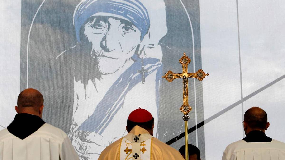 A portrait of Mother Teresa is pictured behind a crucifix, during a holy Mass dedicated to her on the main square in Skopje, Macedonia, Sunday, Sept 11, 2016. Hundreds of people gathered Sunday at the main square in Macedonian capital Skopje for a ceremony of gratitude dedicated to Mother Teresa who Pope Francis has declared a saint last week in Vatican. (AP Photo/Boris Grdanoski)