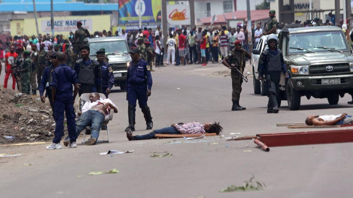 The bodies of people killed during election protests lie in the street, as Congolese troops stand near by in Kinshasa, Democratic Republic of Congo, Monday, Sept. 19, 2016. Witnesses say at least four people are dead after opposition protests against a delayed presidential election turned violent in Congo's capital. The protests were organized by activists who are opposed to longtime President Joseph Kabila, who is now expected to stay in office after his mandate ends in December. (AP Photo/John Bompengo)