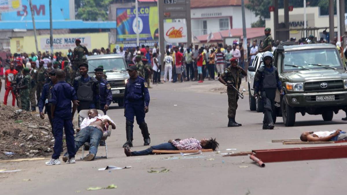 The bodies of people killed during election protests lie in the street, as Congolese troops stand near by in Kinshasa, Democratic Republic of Congo, Monday, Sept. 19, 2016. Witnesses say at least four people are dead after opposition protests against a delayed presidential election turned violent in Congo's capital. The protests were organized by activists who are opposed to longtime President Joseph Kabila, who is now expected to stay in office after his mandate ends in December. (AP Photo/John Bompengo)