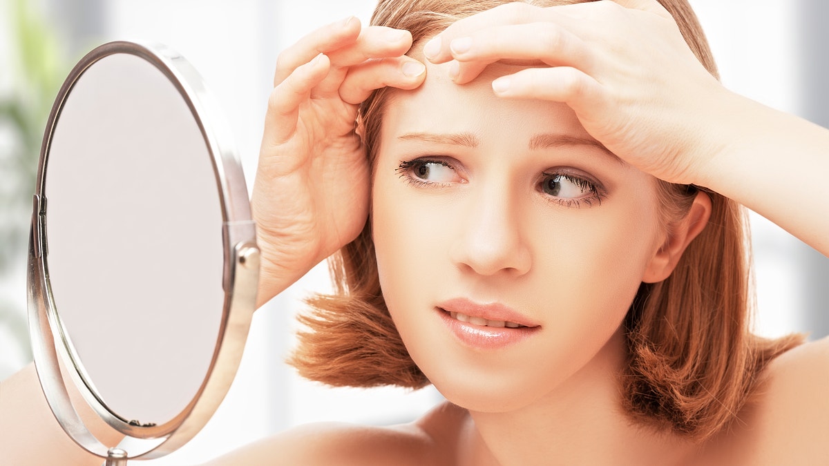 beautiful healthy woman  frightened saw in the mirror acne and wrinkles