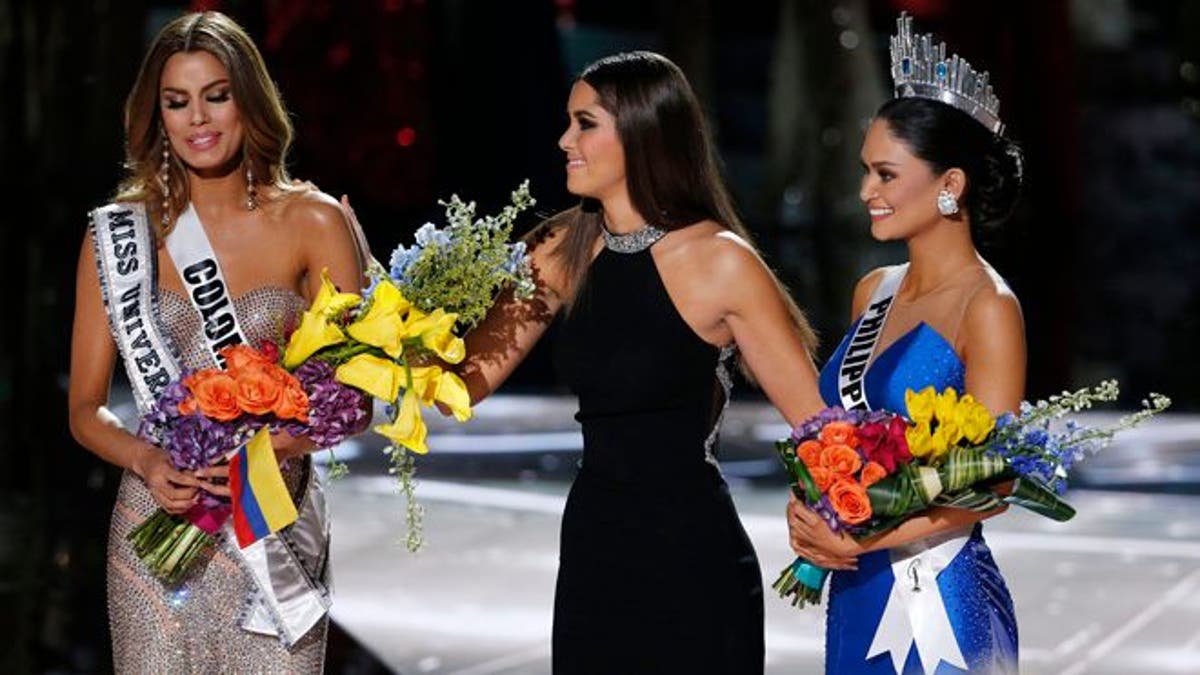 Former Miss Universe Paulina Vega, center, takes away the flowers and sash from Miss Colombia Ariadna Gutierrez, left, before giving them to Miss Philippines Pia Alonzo Wurtzbach, right, at the Miss Universe pageant on Sunday, Dec. 20, 2015, in Las Vegas. Gutierrez was incorrectly named the winner before Wurtzbach was given the Miss Universe crown. (AP Photo/John Locher)