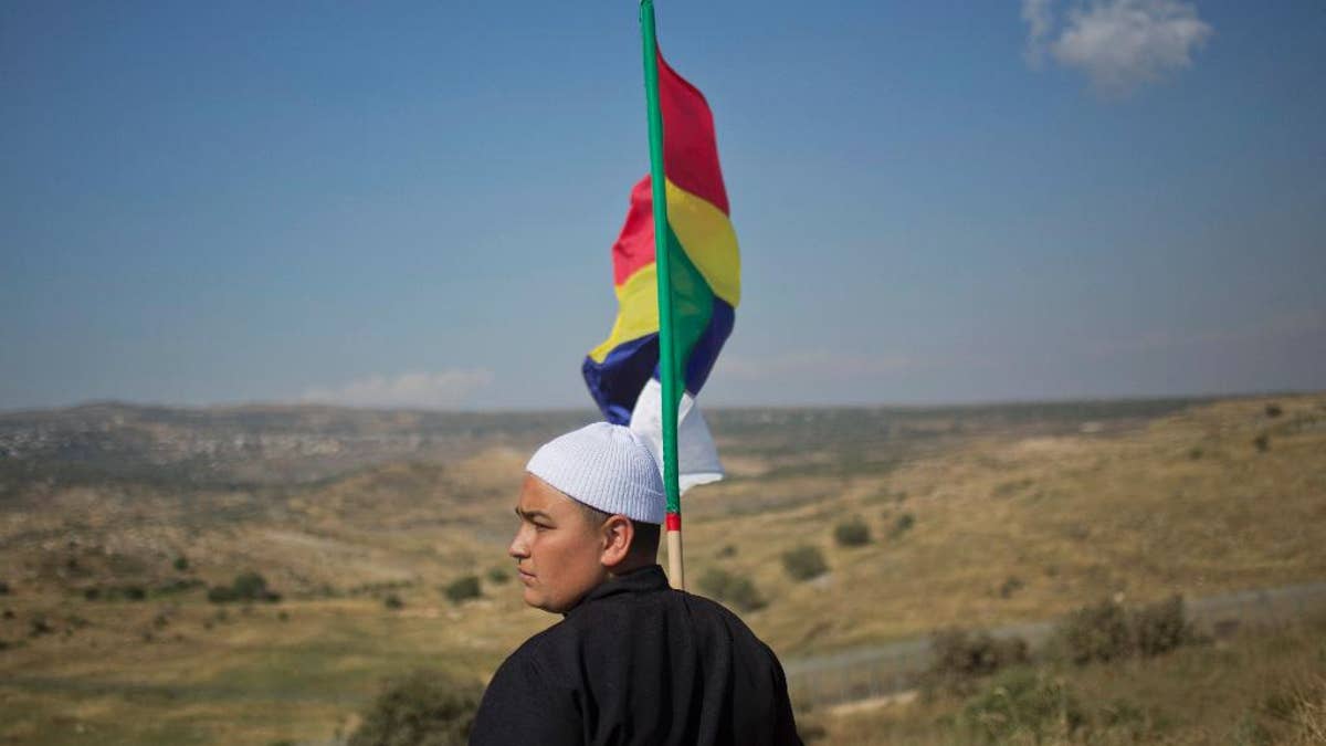 In this photo taken on Wednesday, June 17, 2015, a young member of the minority of Druze Waves the Druze flag while looking at the fights between the forces faithful to the Syrian president Bashar Assad and the rebels in the village of Druze in Khader in Syria, of the Golan Healts controlled by Israeli. The Israeli government insists on the fact that it will not allow the Druze to be massacred but in other words silence, seeking to maintain the low profile which he kept since the start of Assad in March 2011. (AP photo / Ariel Schalit)
