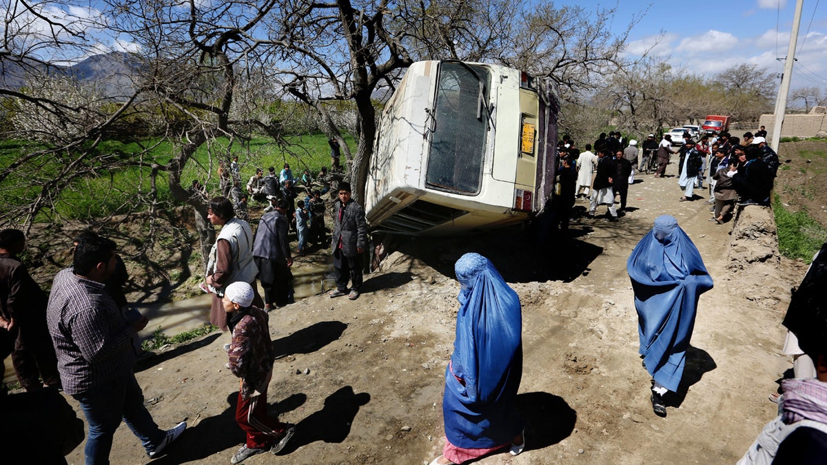 In this Monday, April 11, 2016. file, photo, Afghan women walk past a damaged bus after a roadside bomb explosion on the outskirts of Kabul, Afghanistan, The Afghan Taliban have announced the start of their warm-weather fighting season, an annual declaration that marks the launch of a summer of violence. (AP Photo/Rahmat Gul)