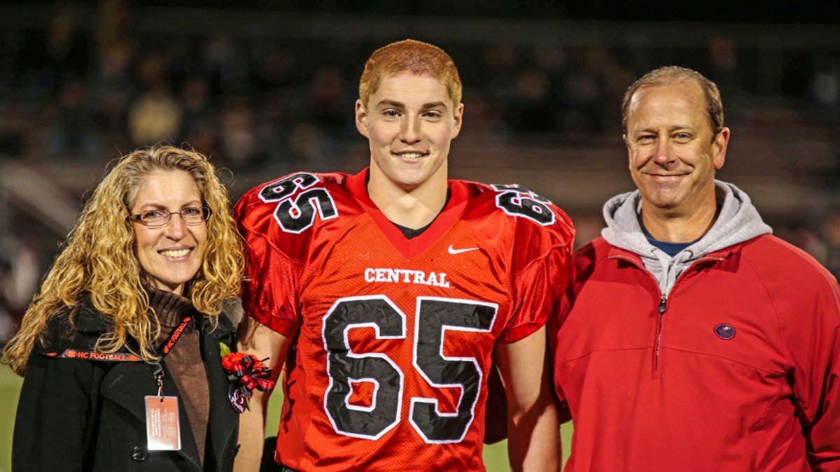 This Oct. 31, 2014, photo provided by Patrick Carns shows Timothy Piazza, center, with his parents Evelyn Piazza, left, and James Piazza, right, during Hunterdon Central Regional High School football's 