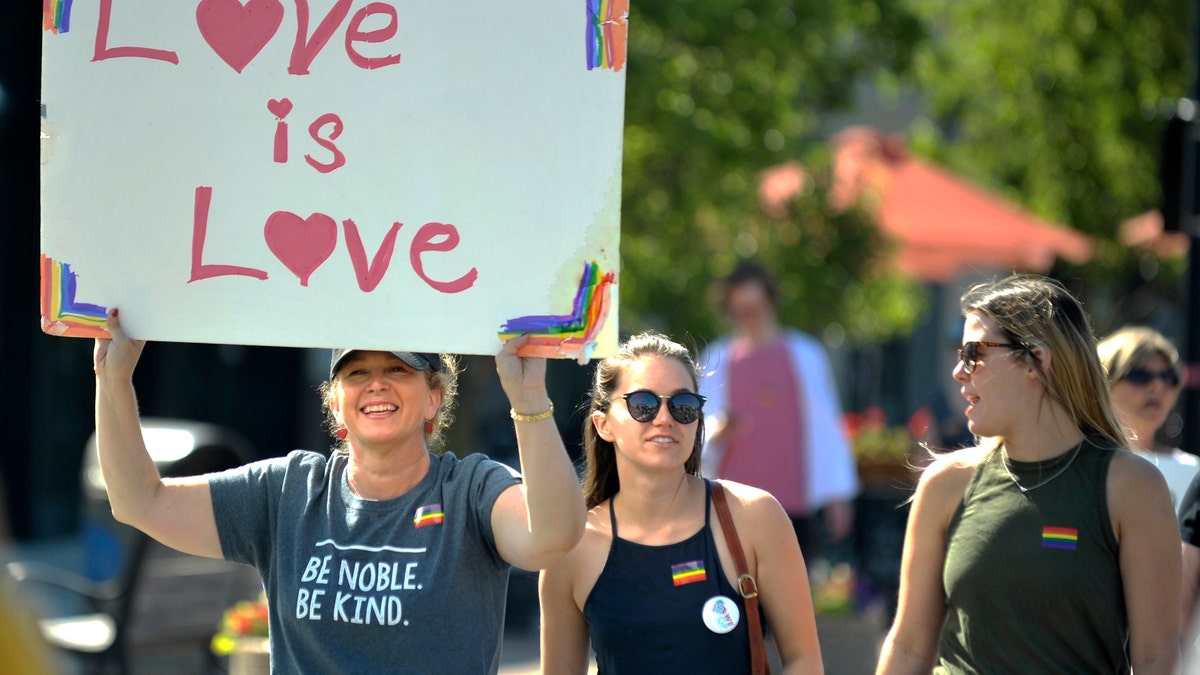 Suzy Berschback, 54, of Grosse Pointe Farms, carries a Love is Love sign as she marches with her daughter, Maddie Berschback and her friend, Kelsie Silzell, both 23. Hundreds participate in the 1st Annual Grosse Pointe Pride March, hosted by Welcoming Everyone Grosse Pointe (We GP), as they march South on Kercheval to west on St. Clair Ave., Sunday, June 11, 2017, in conjunction with National Pride Day. (Todd McInturf/Detroit News via AP)