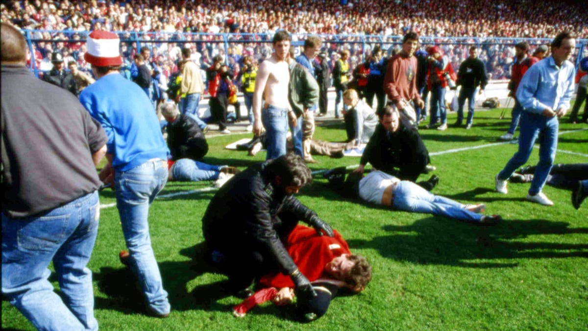 FILE - In this April 15, 1989 file photo, police, stewards and supporters tend and care for wounded supporters on the pitch at Hillsborough Stadium, in Sheffield, England. British prosecutors on Wednesday June 28, 2017, are set to announce whether they plan to lay charges in the deaths of 96 people in the Hillsborough stadium crush _ one of Britainâs worst-ever sporting disasters. (AP Photo, File)