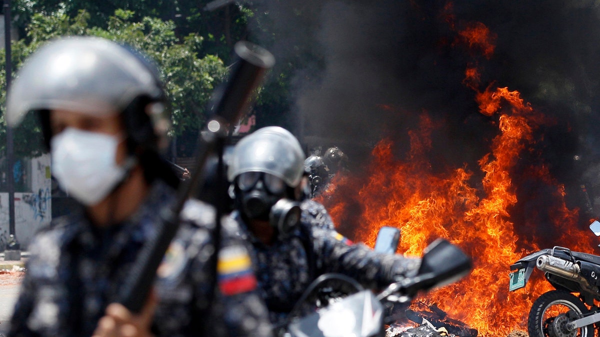 Venezuelan Bolivarian National police move away from the flames after an explosion at Altamira square during clashes against anti-government demonstrators in Caracas, Venezuela, Sunday, July 30, 2017. The explosion injured several officers and damaged several of their motorcycles. The officers were then seen throwing several privately owned motorcycles into the remaining fire in reprisal. (AP Photo/Ariana Cubillos)