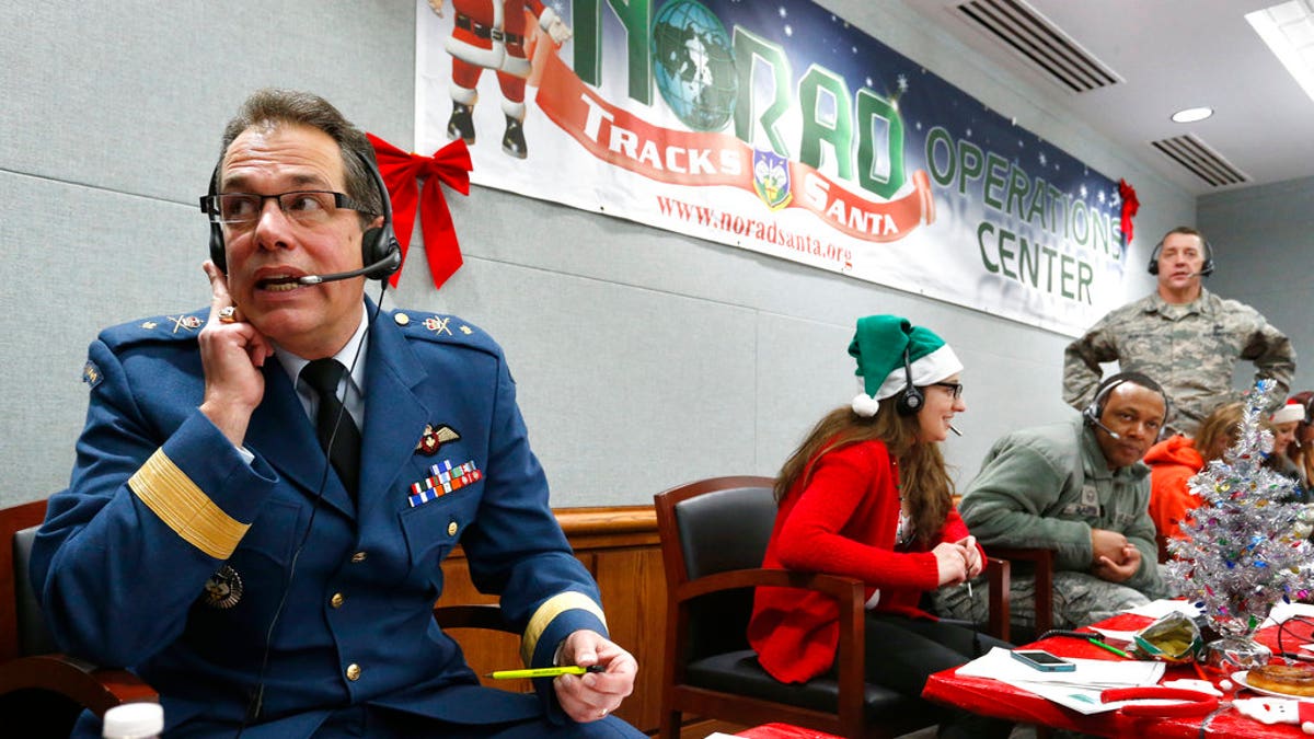 FILE - In this Dec. 24, 2014, file photo, Canadian Brig. Gen. Guy Hamel, NORAD and USNORTHCOM Deputy Director of Policy, Strategy, and Plans, joins other volunteers taking phone calls from children around the world asking where Santa is and when he will deliver presents to their homes, inside a phone-in center during the annual NORAD Tracks Santa Operation, at the North American Aerospace Defense Command, at Peterson Air Force Base, Colo. Hundreds of military and civilian volunteers at NORAD are estimated to field more than 100,000 calls this year throughout Christmas Eve, from children from all over the world eager to hear about Santa's progress. (AP Photo/Brennan Linsley, file)