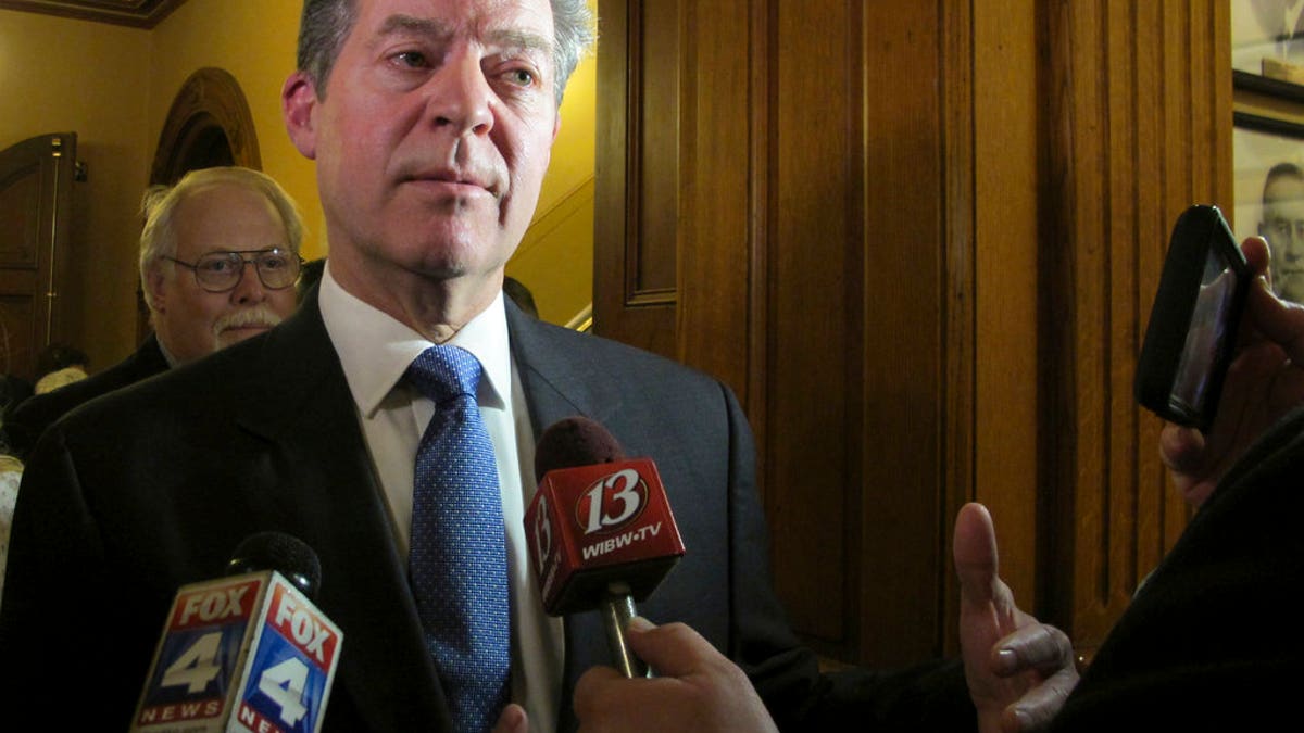 In this Jan. 9, 2018 photo, Kansas Gov. Sam Brownback speaks to reporters following his State of the State address, at the Statehouse in Topeka, Kan. Brownback is drawing criticism from fellow Republicans in the Legislature over his budget proposals. (AP Photo/John Hanna)