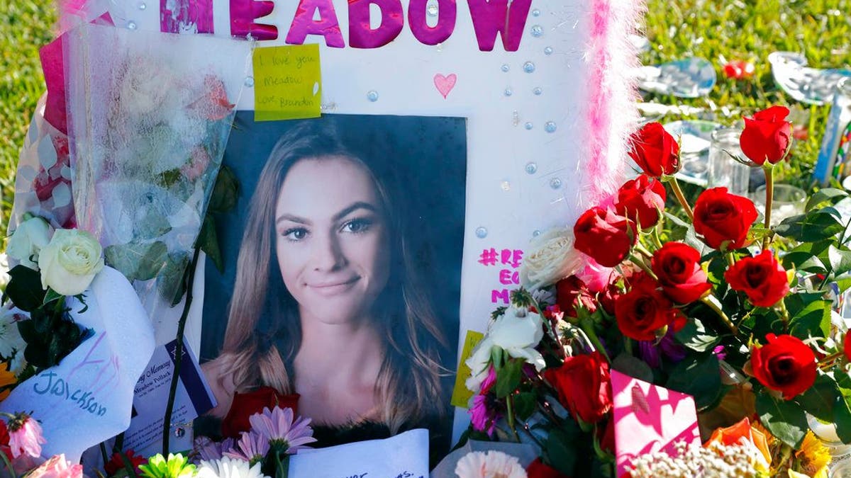 This Feb. 17, 2018 photo shows a photo of Meadow Pollack, one of the seventeen victims who was killed in the Wednesday, Feb. 14, 2018, shooting at Marjory Stoneman Douglas High School, sits against a cross as part of a public memorial, in Parkland, Fla. Nikolas Cruz, a former student, was charged with 17 counts of premeditated murder on Thursday. (AP Photo/Gerald Herbert)